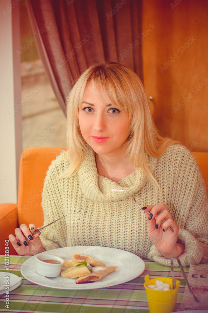 Middle-age woman with pancake and latte coffee for breakfast. Woman enjoying coffee after hours, woman having breakfast in a cozy cafe in the early morning, Autumn mood, Christmas mood Middle-age woman with pancake and latte coffee for breakfast. Woman enjoying coffee after hours, woman having breakfast in a cozy cafe in the early morning, Autumn mood, Christmas mood