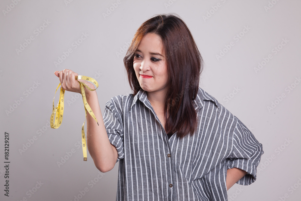 Unhappy young Asian woman with measuring tape. Unhappy young Asian woman with measuring tape.