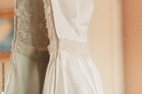 Wedding dress hanging on the wardrobe in the bedroom. The wedding collection. Classic expensive dress for a wedding or celebration in the room of an expensive hotel. Closeup. Vintage tonted photo.
