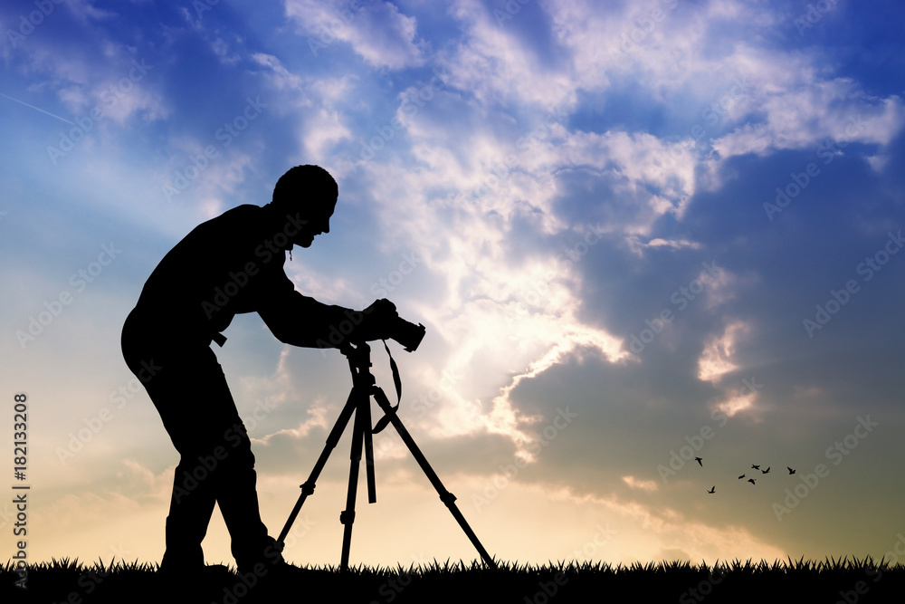 man with camera on tripod at sunset