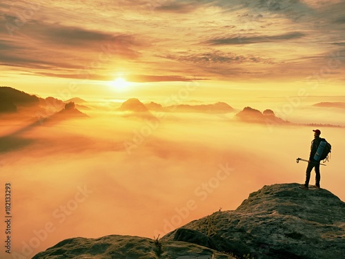 Man silhouette with poles in hand. Sunny spring daybreak and tourist guide stay on sharp cliff of mountain.