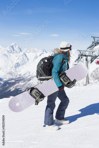 Snowboarder girl on the background of the mountains.