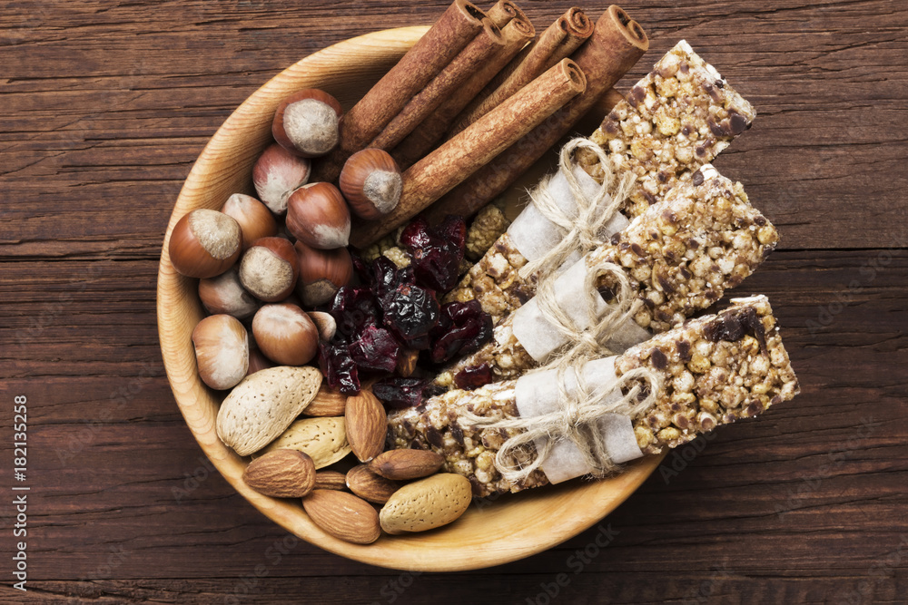Cereal bars with nuts, berries and cinnamon on a wooden background. Top view. Food background Cereal bars with nuts, berries and cinnamon on a wooden background. Top view. Food background
