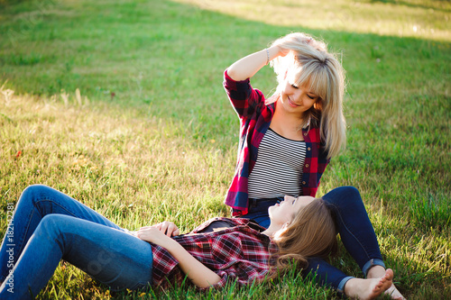 Two happy female friends playing and having fun in green grass