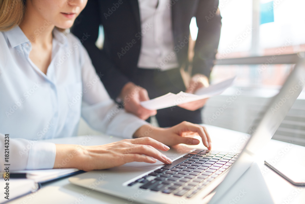 Businesswoman networking by desk on background of her colleague with paper Businesswoman networking by desk on background of her colleague with paper