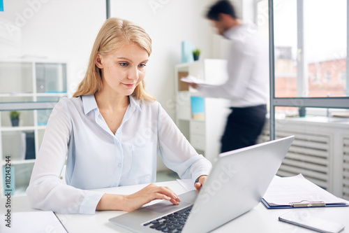 Confident female watching online seminar in working environment of office