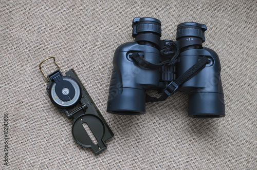 Military binoculars and compass, traveler's things, on sackcloth background photo