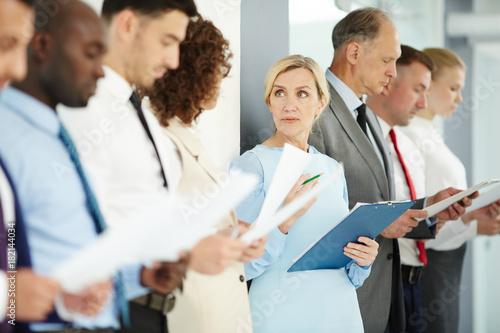 Mature expert consulting one of employees while standing in queue