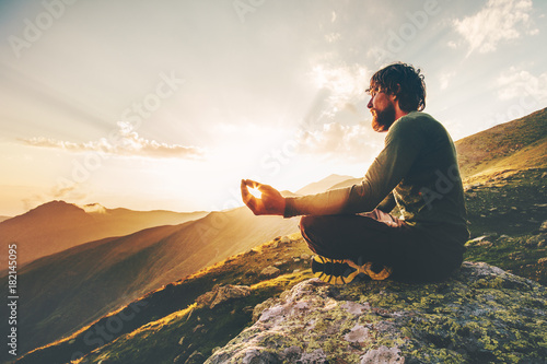 Man meditating yoga lotus pose at sunset mountains Travel Lifestyle relaxation emotional concept summer vacations outdoor harmony with nature calm scene photo