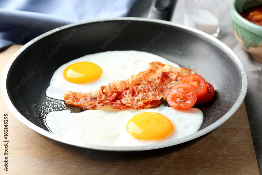 Frying pan with eggs, bacon and tomatoes on table Frying pan with eggs, bacon and tomatoes on table