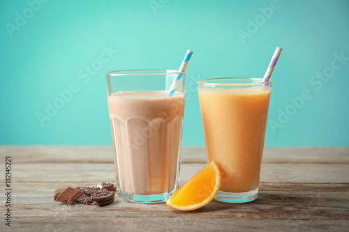 Orange and chocolate milkshakes in glasses on table