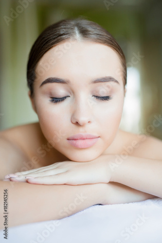 Relaxed woman with closed eyes having massage of her body in spa salon