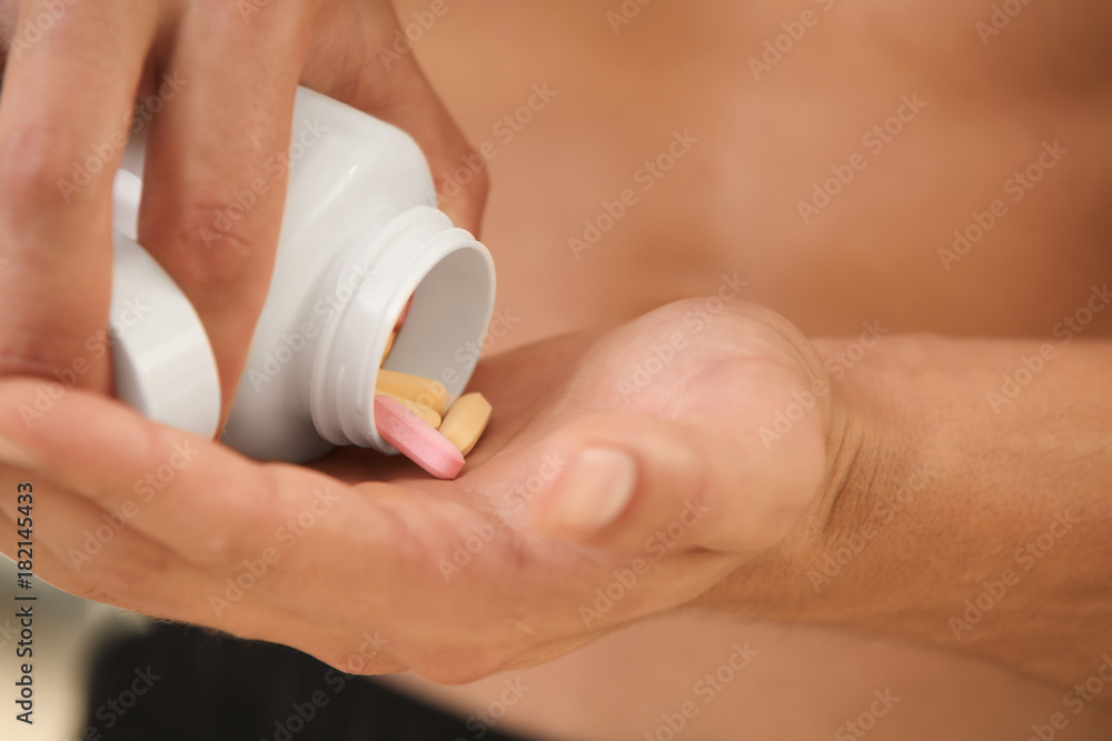 Muscular young man taking pills, closeup Muscular young man taking pills, closeup