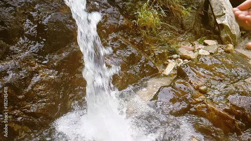 Female hands take drinking water from nature waterfal