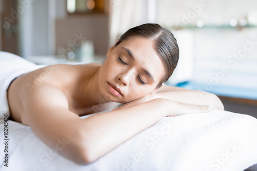 Young peaceful woman having rest after massage of her body in professional salon