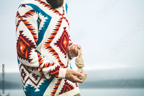 Man hands holding rope knot Travel Lifestyle survival concept wearing knitted sweater outdoor foggy nature on background