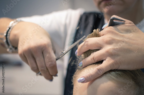Close up of hairdresser cutting hair of a small boy.