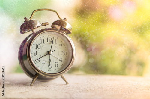 alarm clock showing time 6 am with morning sunlight and colorful bokeh ,nature background 