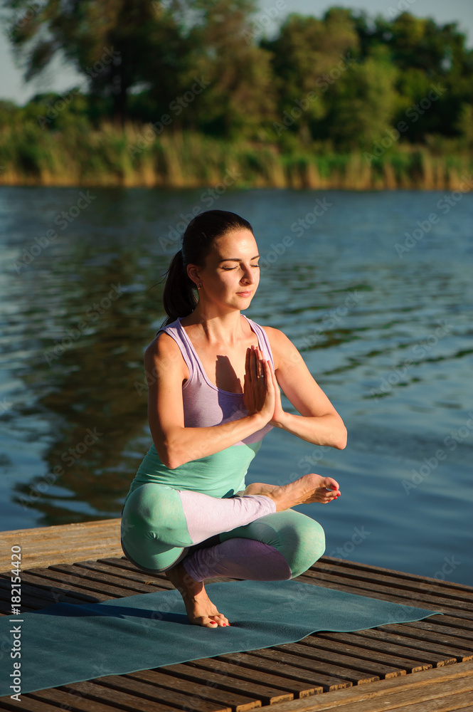 Young healthy woman practicing yoga at sunset