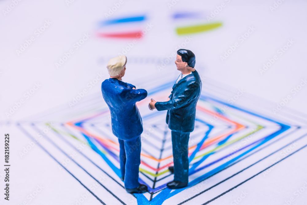 Miniature People : Businessman standing on a Paper graph chart ,Developing a teamwork concept Miniature People : Businessman standing on a Paper graph chart ,Developing a teamwork concept
