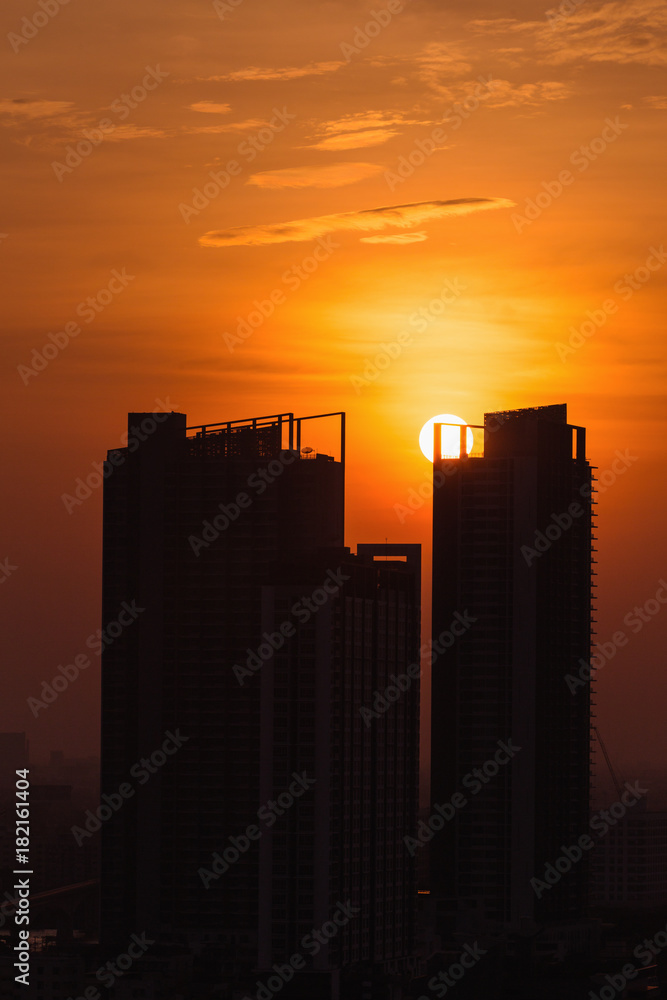 Vertical scene of silhouetted tower with bright sky of golden hour with sunset at Bangkok city of Thailand.