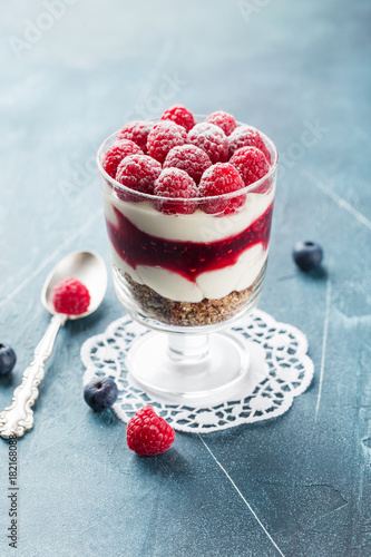 Bilde på lerret Single trifle with raspberry and blueberry in a glass on white napkin on blue ba