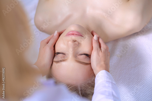 Young woman lying on a massage table,relaxing with eyes closed. Woman. Spa salon