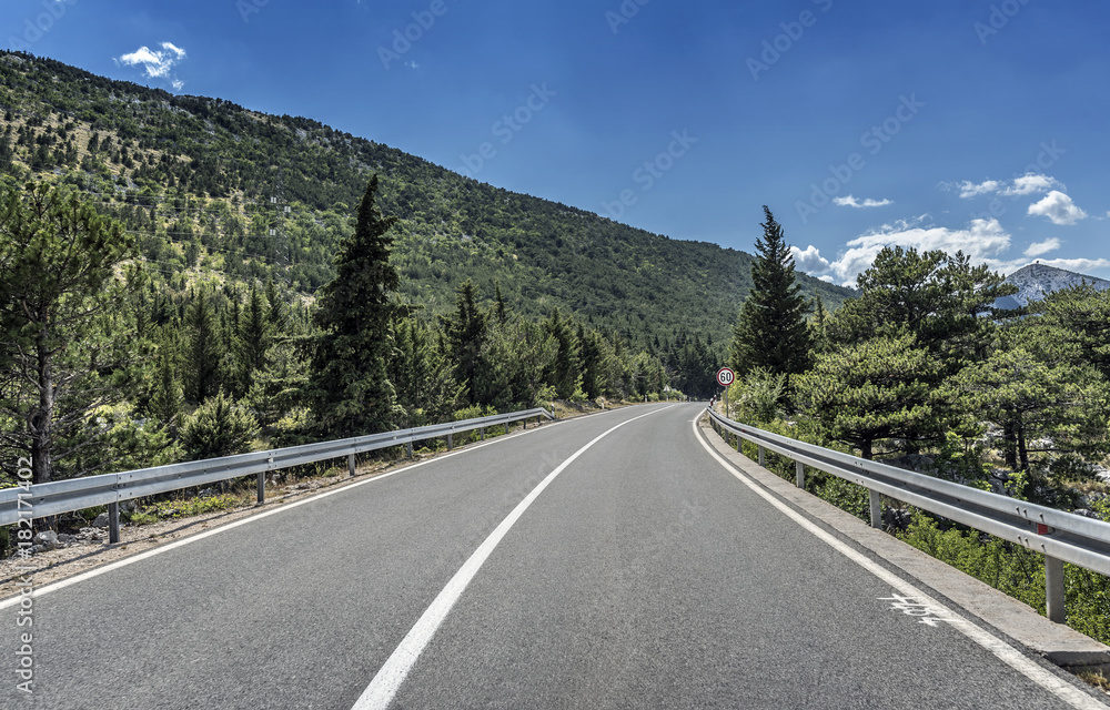 Country road through the rocky mountains and forest.