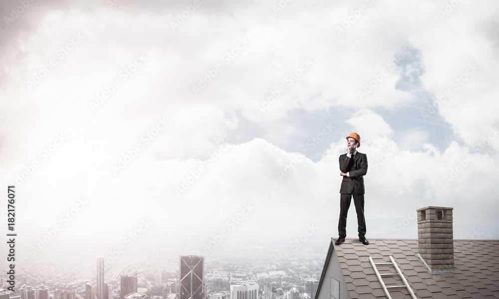 Engineer man standing on roof and looking away. Mixed media Engineer man standing on roof and looking away. Mixed media