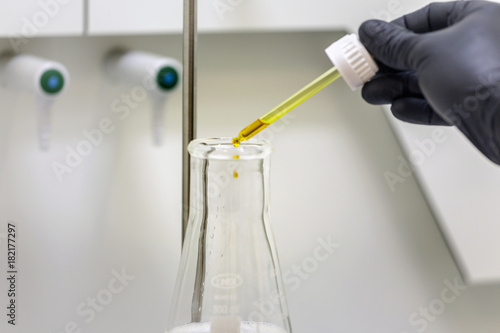 Professional laboratory with a men hand dropping liquid into a galss