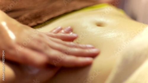 girl doing abdominal massage with oil. Ayurvedic healing massage. close-up shot of abdominal massage of a womans body, master is doing motions and covering by towel