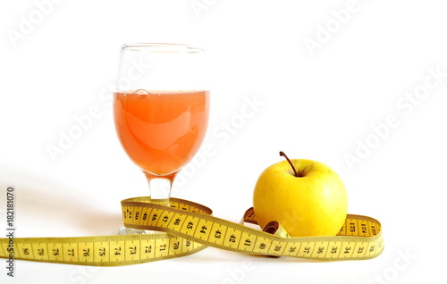 measuring tape, a glass of freshly squeezed orange juice and yellow apple isolated on white background