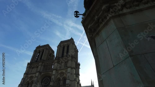 The Notre Dame in Paris in a moving camera shot with streetlights and trees in the front. photo