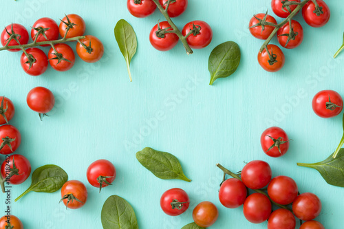 Fototapeta Naklejka Na Ścianę i Meble -  Top view on bunches of cherry tomatoes with basil leaves on turquoise wooden background. Healthy food.