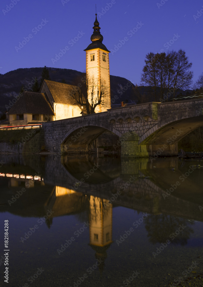 Bohiji Lake and Church of St. John the Baptist with arched bridge and reflection in dusk time, Triglav National Park,  Julian Alps, Slovenia