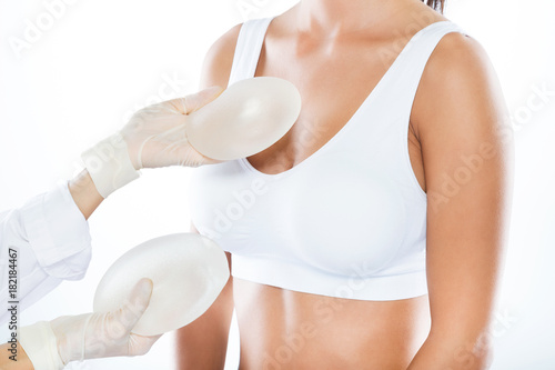 Female doctor choosing mammary prosthesis with her patient over white background. photo