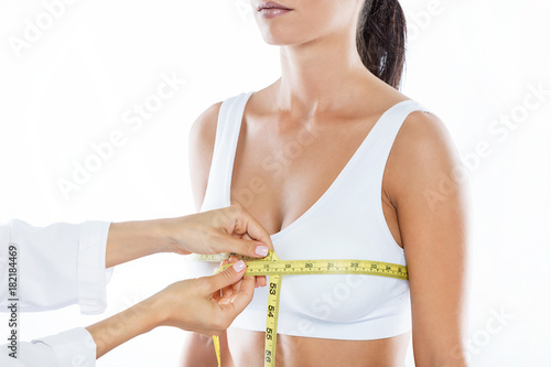 Doctor with measure tape measuring the size of the patient's breast.