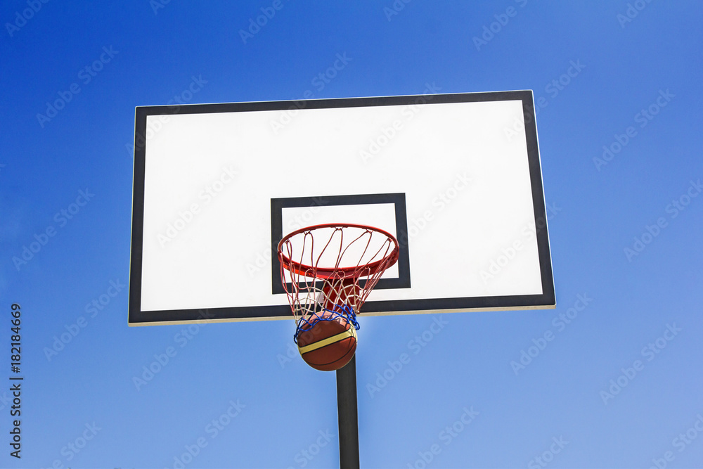 Basketball ball hit the basket in the blue sky background Basketball ball hit the basket in the blue sky background