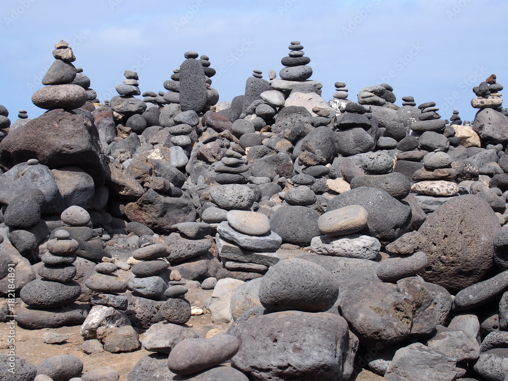 large towers of stacked pebbles on a beach with blue sky large towers of stacked pebbles on a beach with blue sky