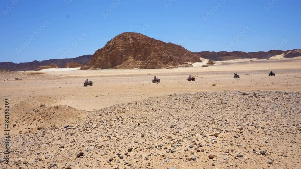 Skyline Aerial view of young men riding quad bikes over sand dunes in desert. The race in difficult conditions on the sand on a quad bike Skyline Aerial view of young men riding quad bikes over sand dunes in desert. The race in difficult conditions on the sand on a quad bike