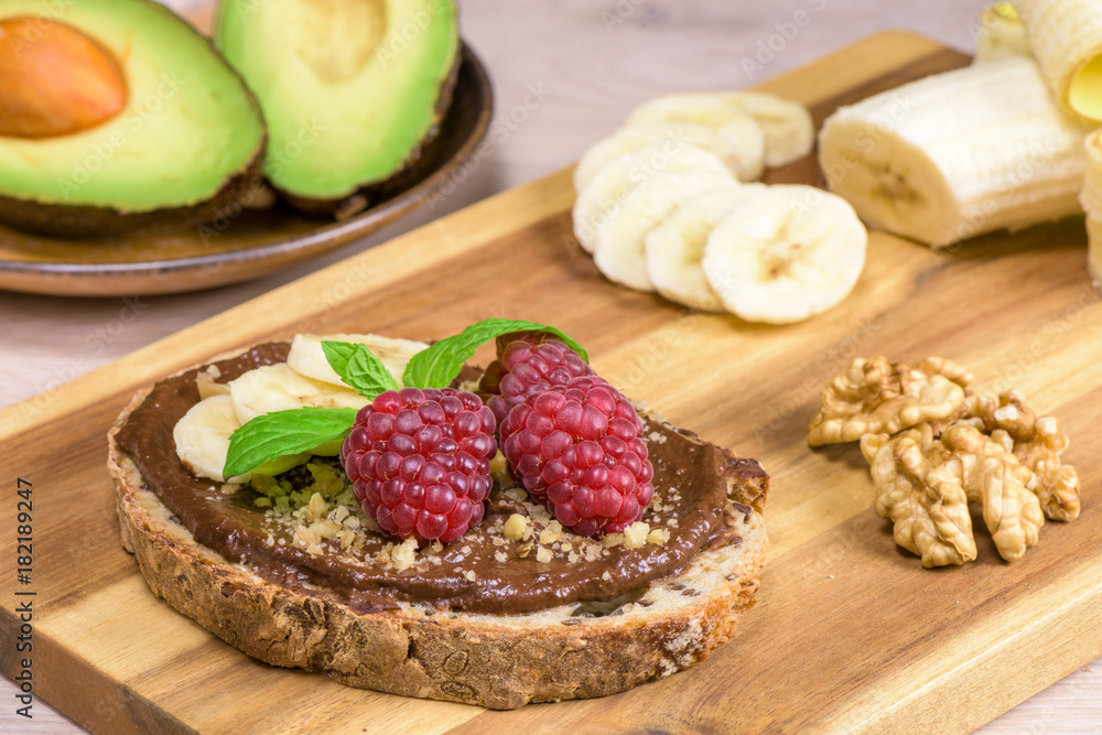 Slice of bread with paleo vegan cream made with avocado, banana, honey, cocoa with raspberries.
