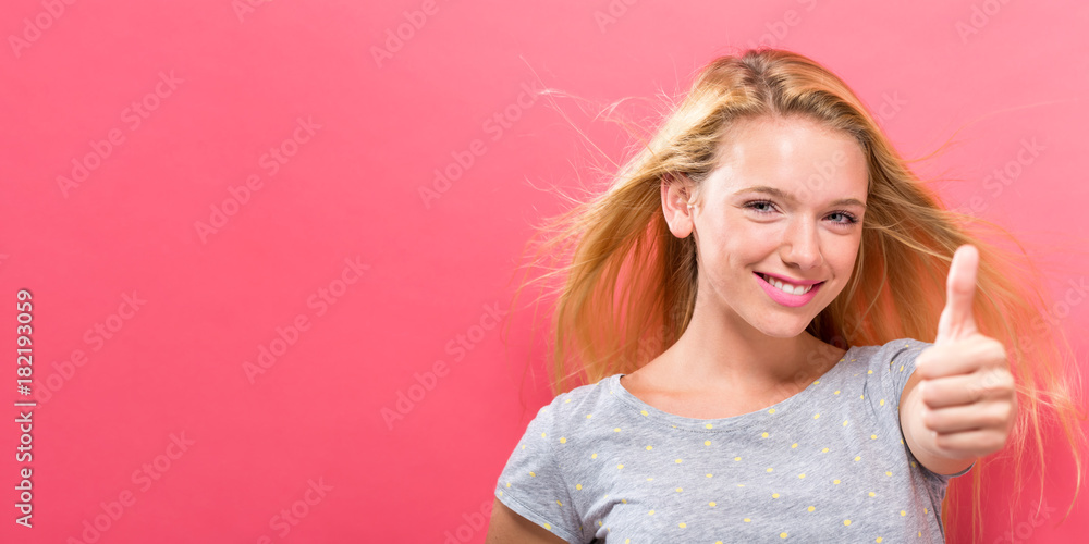Happy young woman giving thumbs up on a solid background Happy young woman giving thumbs up on a solid background