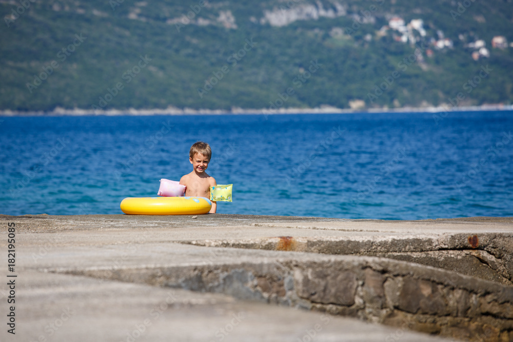 Little boy on the beach with yellow tube.