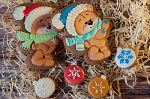 Cute bears drawn on christmas gingerbread laying with honey cookies in shape of balls on wooden table