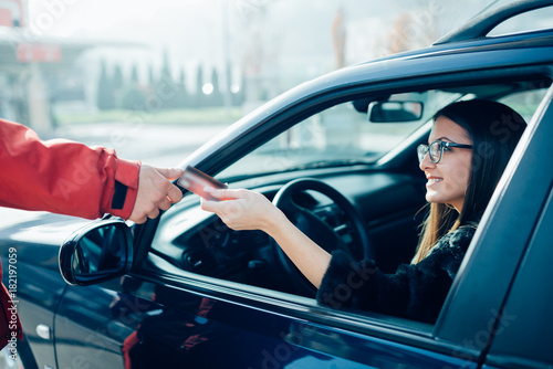 Beautiful woman refueling the gas tank at fuel pump