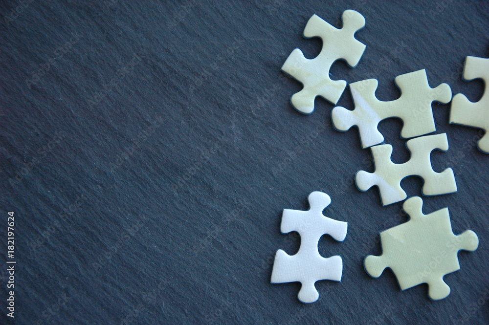 Obraz premium A lot of white and gray puzzles on a black background.