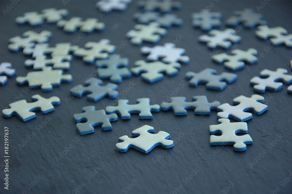A lot of white and gray puzzles on a black background. A lot of white and gray puzzles on a black background.