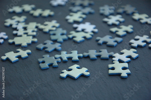 A lot of white and gray puzzles on a black background. © kivitimof