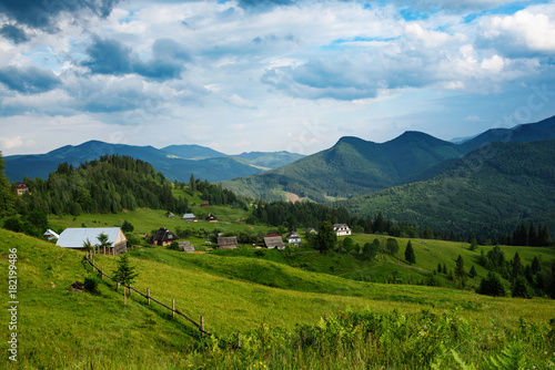 Carpathian mountains summer landscape with cloudy sky and village, natural summer travel background
