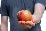 Holding an apple in the palm of a hand with a gray shirt on white background
